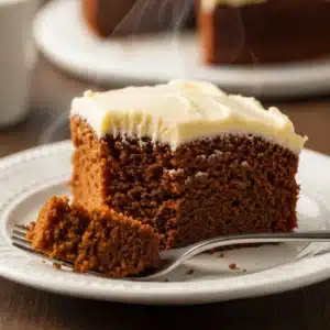 A close-up view of a slice of Spiced Molasses Cake showing the moist crumb and creamy eggnog frosting texture.