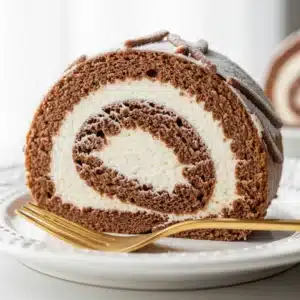 A slice of holiday yule log dessert showing a perfect spiral of chocolate sponge and white mascarpone filling.