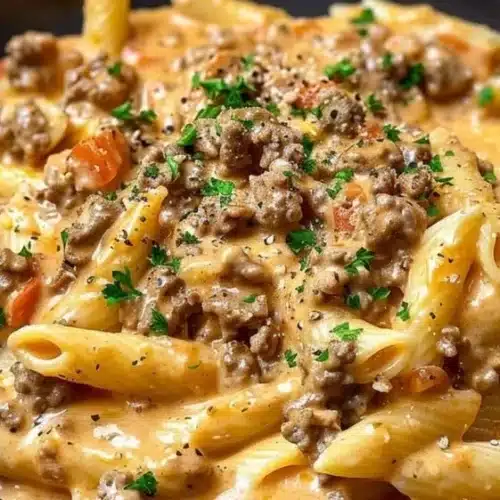 Creamy beef pasta dish served in a bowl, garnished with herbs.